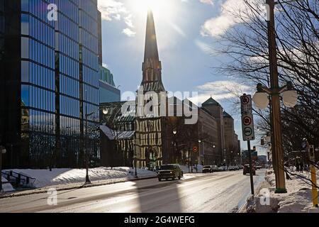 Saint Andrew`s presbytarian church, with sun rays pattern reflecting from the windows of modern glass and steel office building in Ottawa, capital of Stock Photo